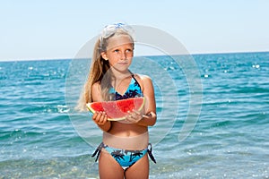 Cute girl eating watermelon on beach.