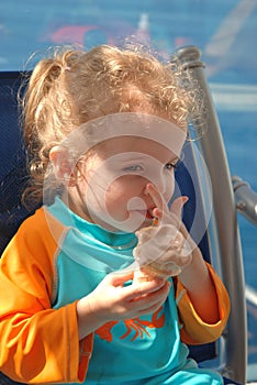 Cute girl enjoys an ice cream cone after swimming