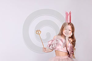 Cute girl in fairy dress with pink crown and magic wand on light grey background, space for text. Little princess