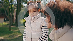 Cute girl feeding pigeons with mother at sunny park close up. Child having fun