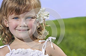 Cute girl with flower on blue sky and green grass