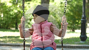 A cute girl about four years old is riding on a swing on a beautiful sunny autumn day in the park. Family day