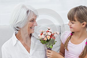 Cute girl giving a bunch of flowers to her grandmother
