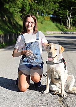 Cute girl with glasses and denim overalls and labrador dog in the summer