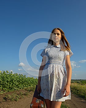 Cute girl goes on a dirt road in field