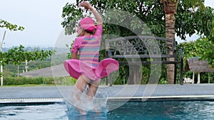 Cute girl with goggles jumping into the pool.