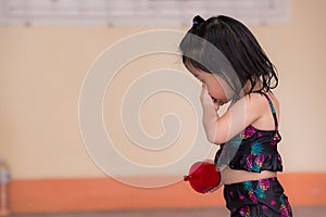 Cute girl got wet from playing in water in front house. Candid baby stroked the water droplets from her face.