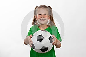 A cute girl in a green t-shirt with a soccer ball in her hand smiles isolated on a white background. A sporty caucasian kid holds