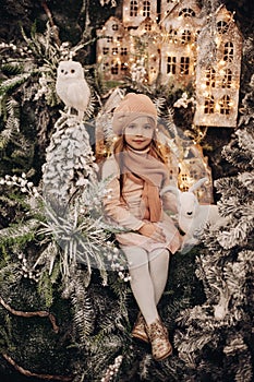 Cute girl in hat and scarf in Christmas decorations.