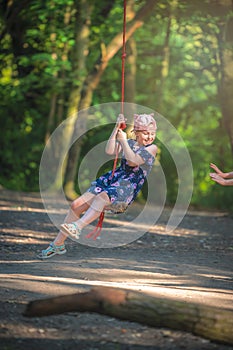 Cute girl having fun on a line swing in summer