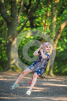 Cute girl having fun on a line swing in summer