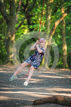 Cute girl having fun on a line swing in summer