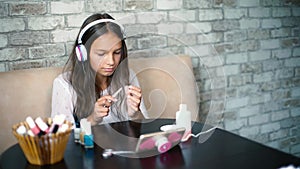 Cute girl in headphones listening music making manicure polishing nails with free and copy space