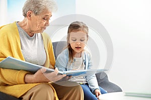 Cute girl and her grandmother reading book
