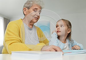 Cute girl and her grandmother reading book