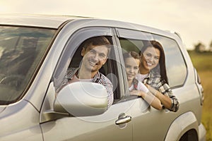 Cute girl with her mom and dad looking out of car windows on road trip. Family with child on auto journey in countryside