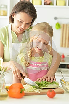Cute girl with her mother cooking together at kitchen table