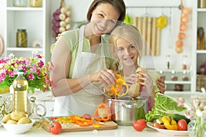 Cute girl with her mother cooking together at kitchen table