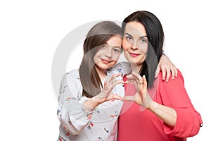 Cute girl and her mother making together heart shape hand gesture. Family love, care and support. Mom and daughter.