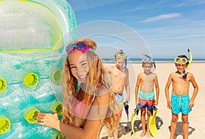 Cute girl hold matrass stand on beach with friends