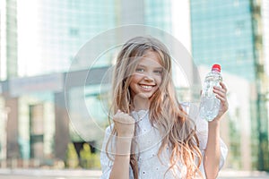 Cute girl holding a bottle of water in the city smiling pumping fist celebrating