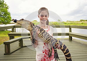 Cute girl holding a crocodile near florida everglades