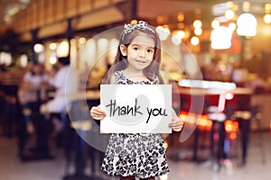 Cute girl holding a piece of paper with the words Thank You