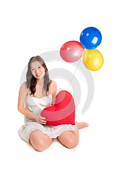 Cute girl holding a red heart pillow, with three colorful balloons above he