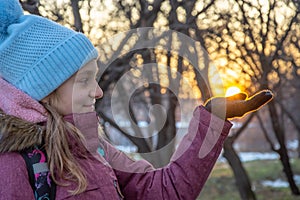 Cute girl holding the sun in the palm in winter park