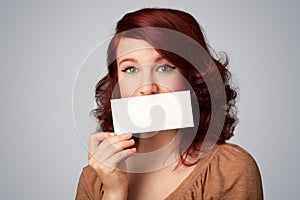 Cute girl holding white card at front of her lips with copy space