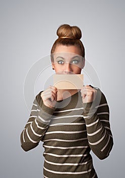 Cute girl holding white card at front of her lips with copy space