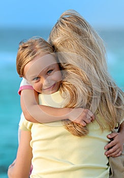 Cute girl hugging her mom on the beach