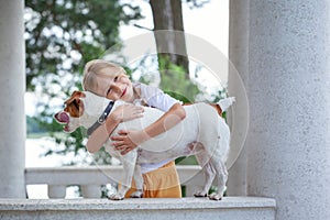 Cute girl hugging Jack Russell Terrier dog in nature. Beautiful dog. Kid and dog friendship
