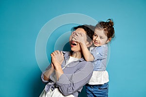 Cute girl hugs her mother covering her eyes with her hands. Emotions. play. love, care, tenderness, happy childhood concept