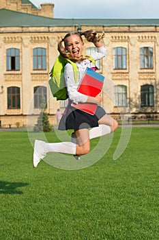 Cute girl jump with notebook. happy preschool girl with book in school yard. back to school. hardworking child carry