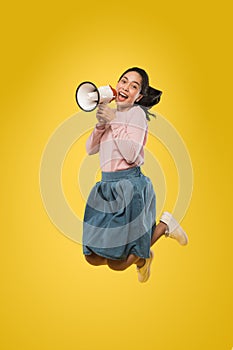 Cute girl jumping and screaming making announcement using megaphone