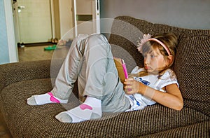 Cute girl kid using iPad digital computer tablet on bed for education or playing game. photo