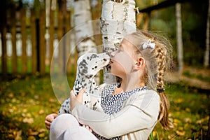 Cute girl kissing her puppy, doggy on the wood fence background.Happy girl with a dog licking her face.real friends