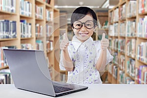 Cute girl with laptop shows thumbs up