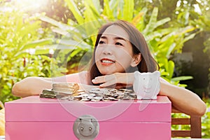 Cute girl likes saving money, happily putting coins in the pig piggy bank.