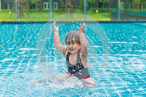 Cute girl or little child playing in swimming pool happily