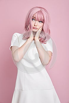 Cute girl with long pink hair, hair coloring. Beautiful woman on a pink background in a white dress. Colored hair, perfect