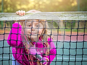 Cute girl looking through tennis net