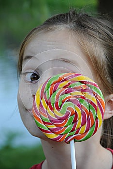 Cute girl lurks behind a giant lolly