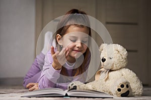 Cute girl lying on the floor and reading a book