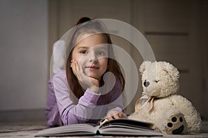 Cute girl lying on the floor and reading a book