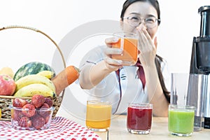 A cute girl makes vegetable juice, with carrot apple orange cranberry beetroot and mango in chef suit