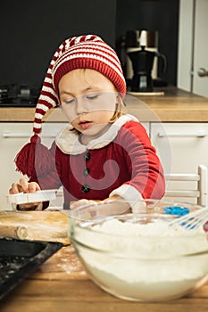 Cute girl making dough for Christmas cookies. Little kid wearing Christmas outfit and having fun while cooking in the kitchen.