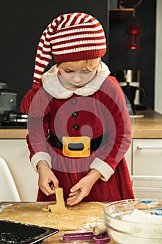 Cute girl making dough for Christmas cookies. Little kid wearing Christmas outfit and having fun while cooking in the kitchen.