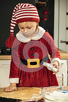 Cute girl making dough for Christmas cookies. Little kid wearing Christmas outfit and having fun while cooking in the kitchen.